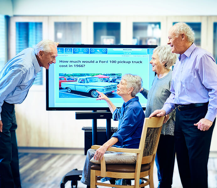 Group of seniors enjoying an interactive activity on the iN2L touchscreen system at Amazing Grace Senior Living