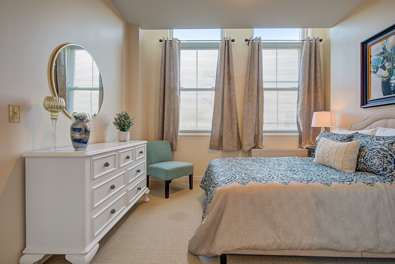 Cozy one-bedroom apartment featuring stylish bedding and warm lighting at Amazing Grace Senior Living