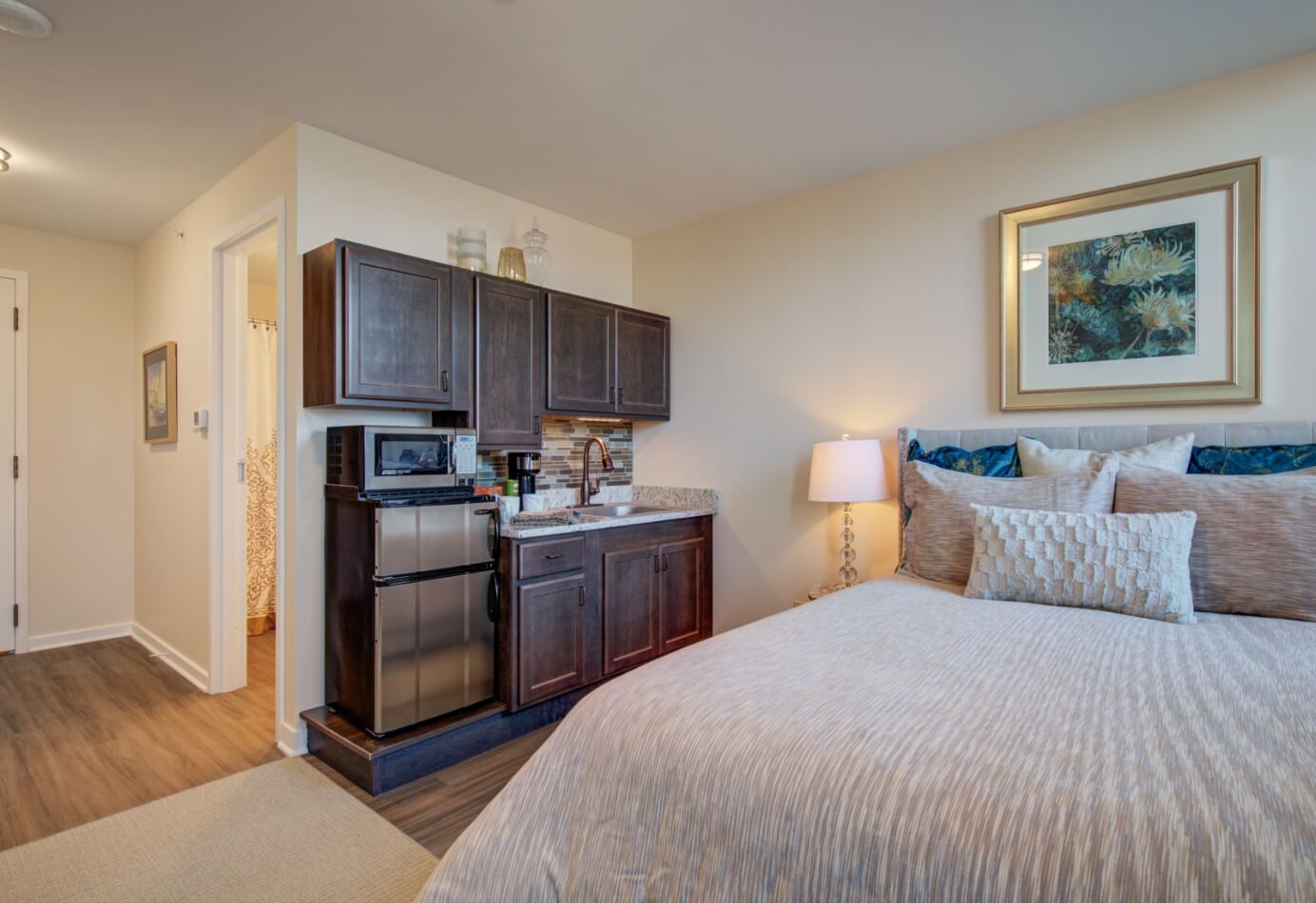Cozy studio apartment at Amazing Grace Senior Living featuring a kitchenette, queen bed, and modern decor